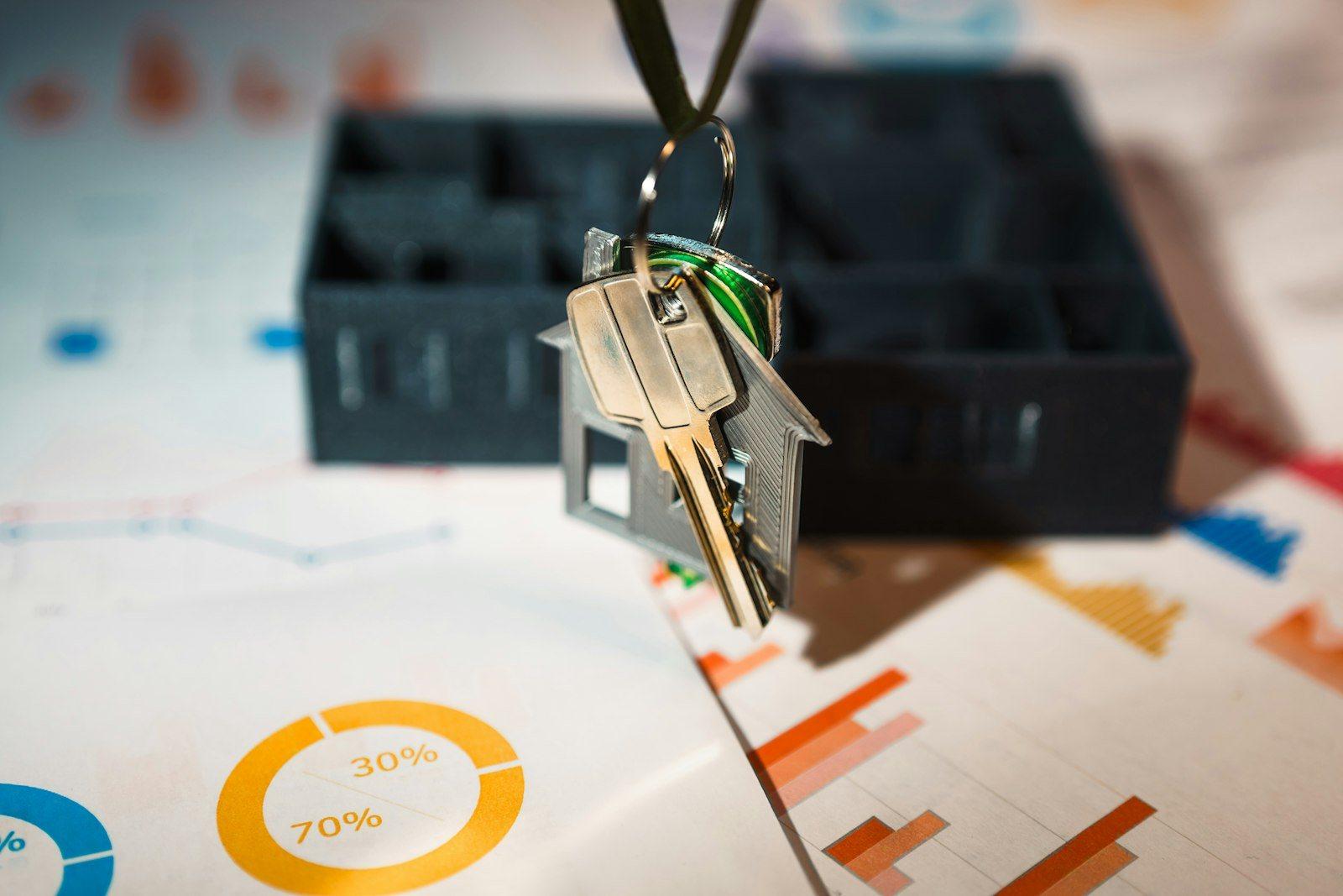 House keys resting on printed property market charts and transaction data